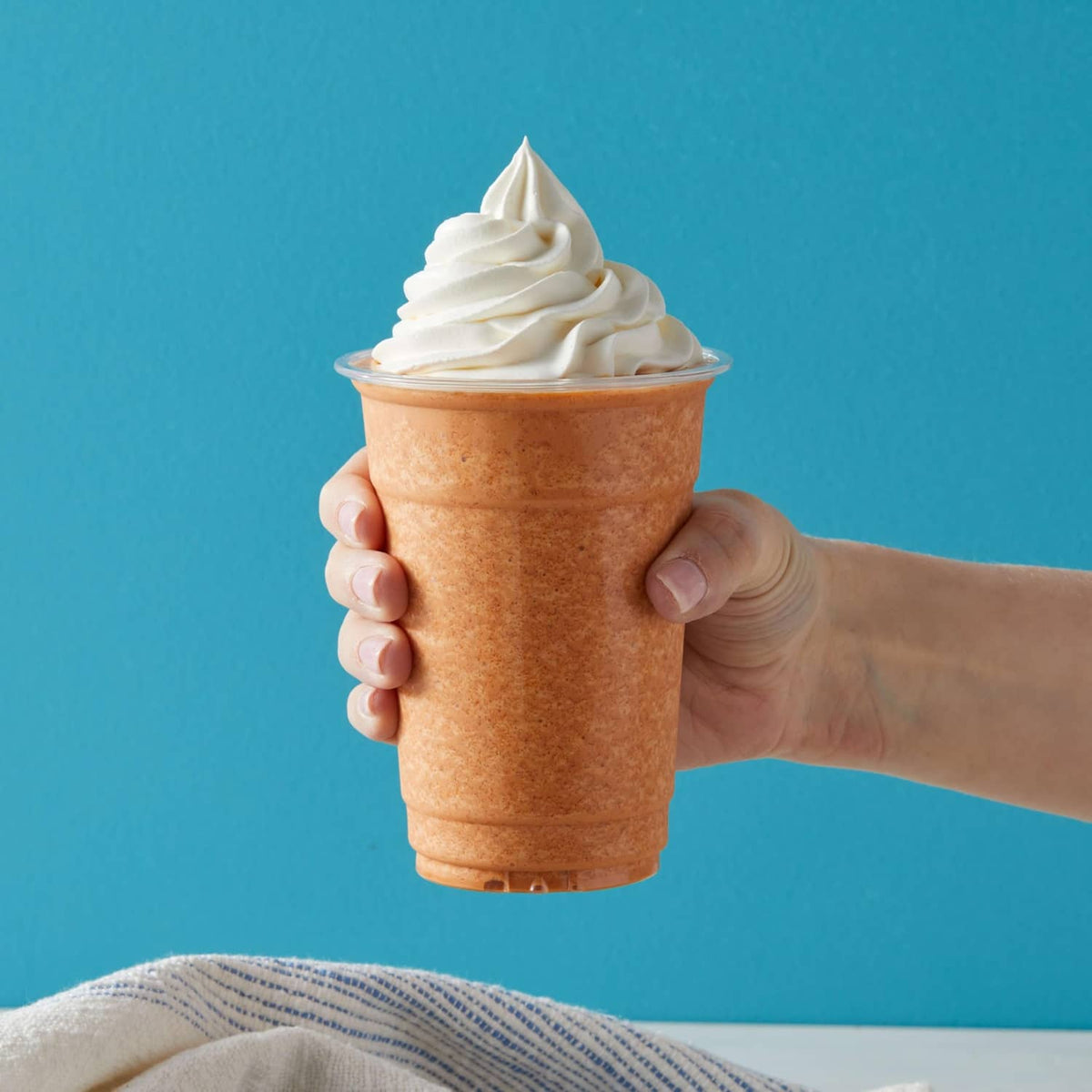 Thai tea blended crème in a plastic cup topped with whipped cream