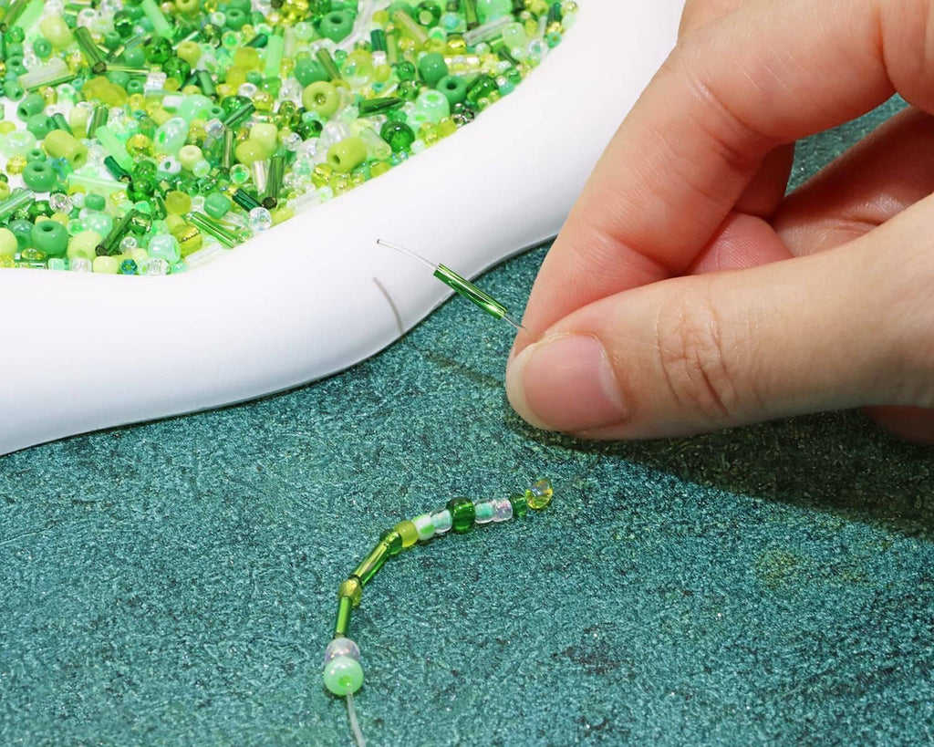Green seed bead strand being threaded, with tube and round beads