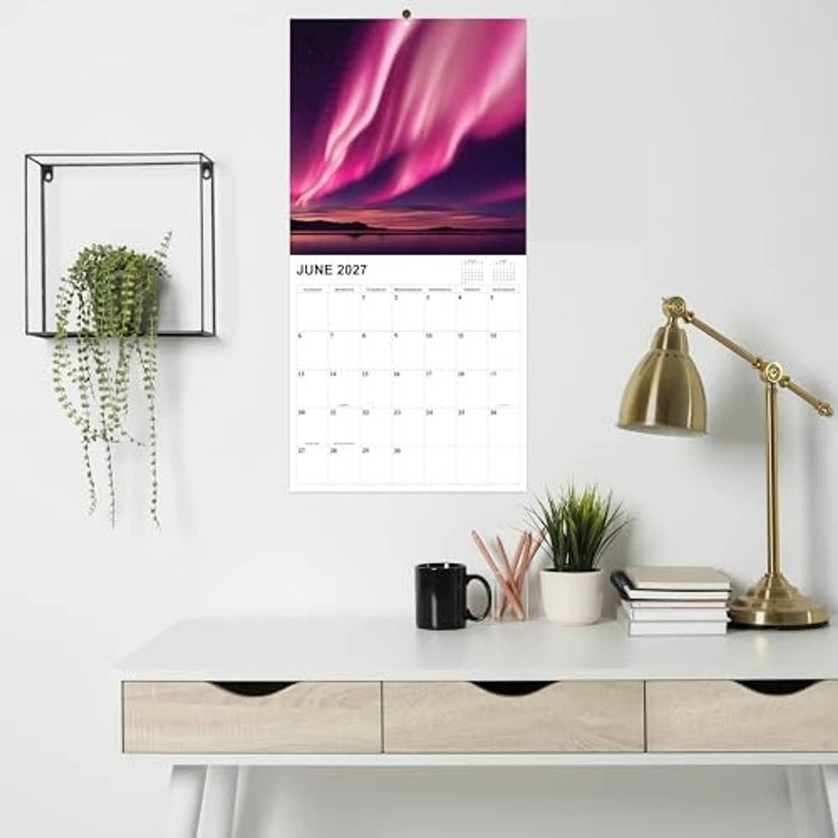 Aurora-themed wall calendar page hanging, showing June 2027 monthly date grid