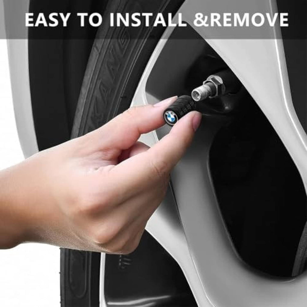 Hand installing a black tire valve stem cap with BMW emblem on a car wheel