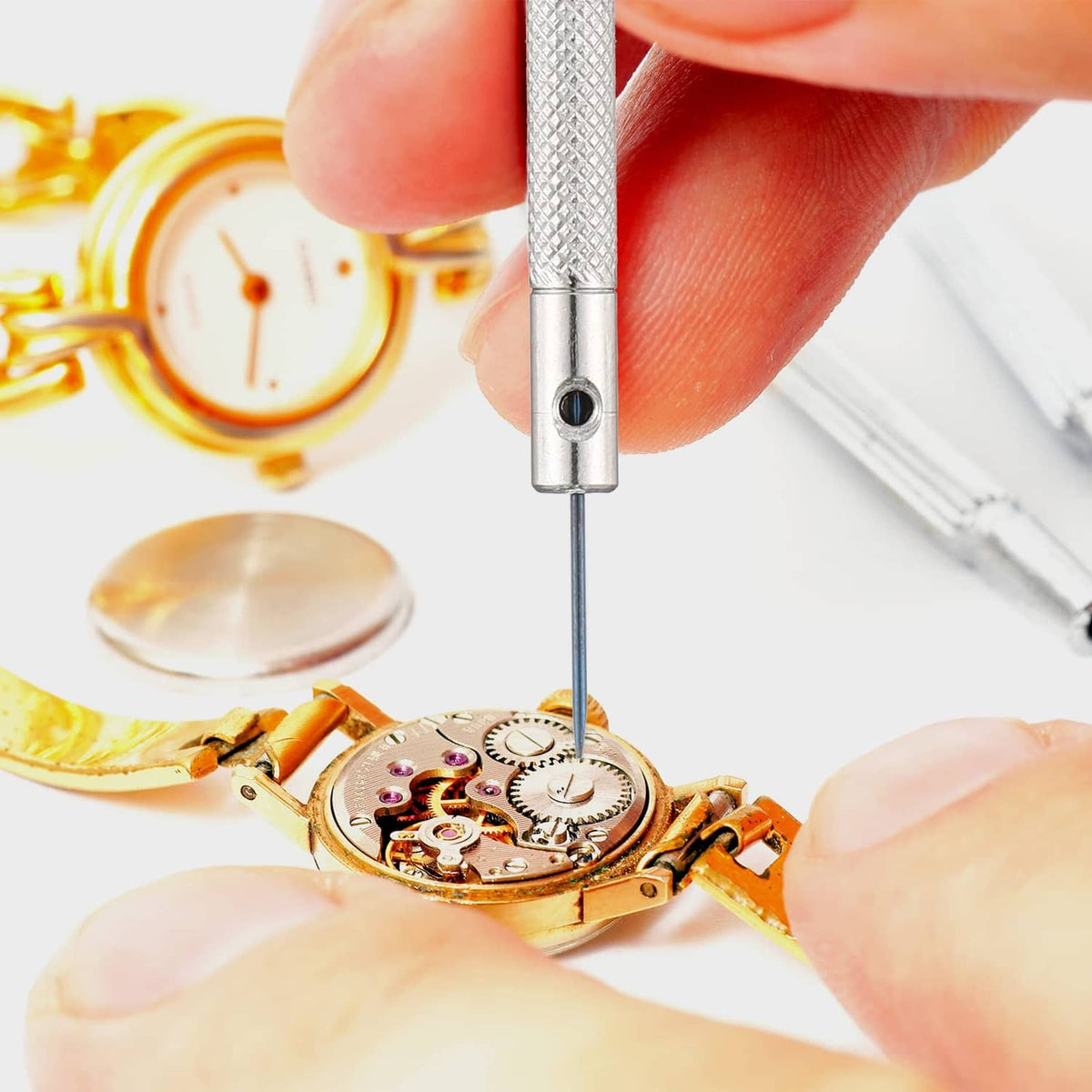 Hand using a micro screwdriver on a gold watch movement circuit board