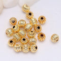Gold-tone corrugated round beads with black center dots, assorted pile