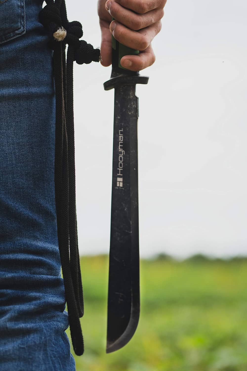 Hooyman bush machete held in hand, green-and-black handle and curved blade