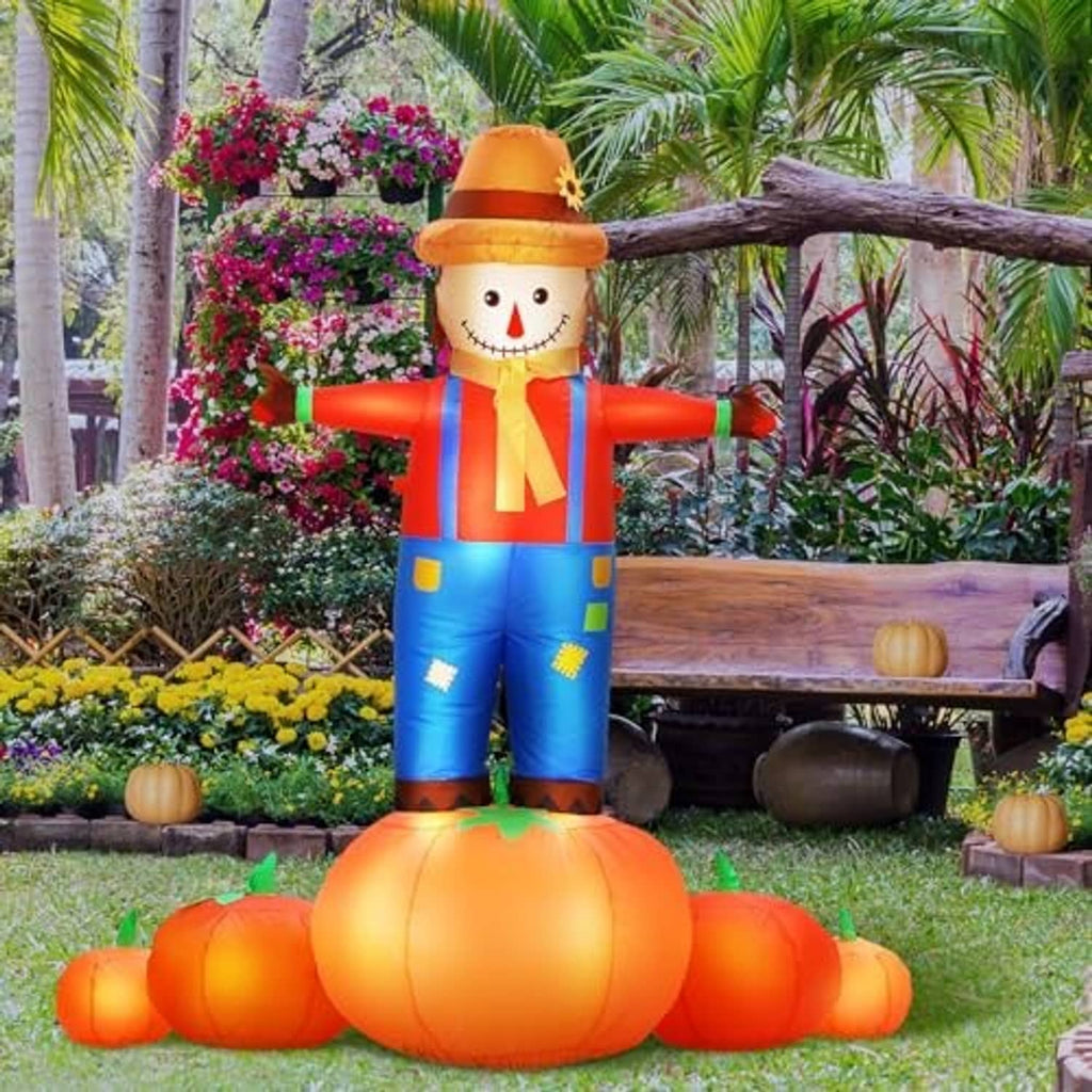 Inflatable scarecrow with pumpkin base in fall garden, orange hat and striped shirt