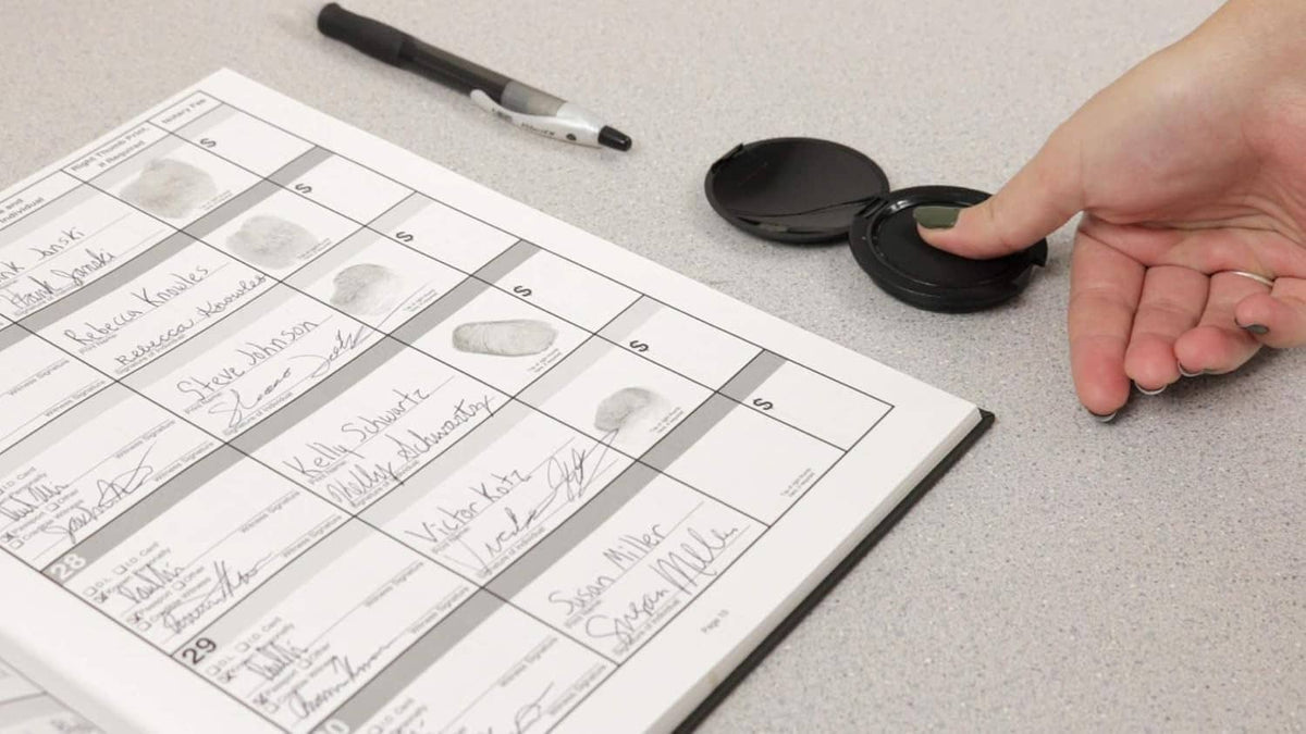 Inkless fingerprint pad on desk beside fingerprint record sheet, hand poised to stamp