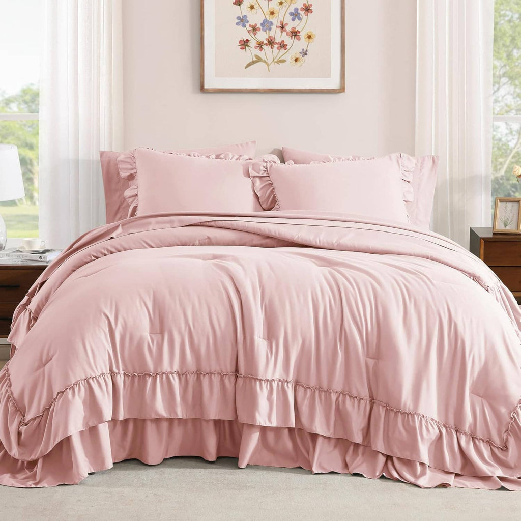 Blush pink queen comforter and pillow shams with layered ruffle trim on bed