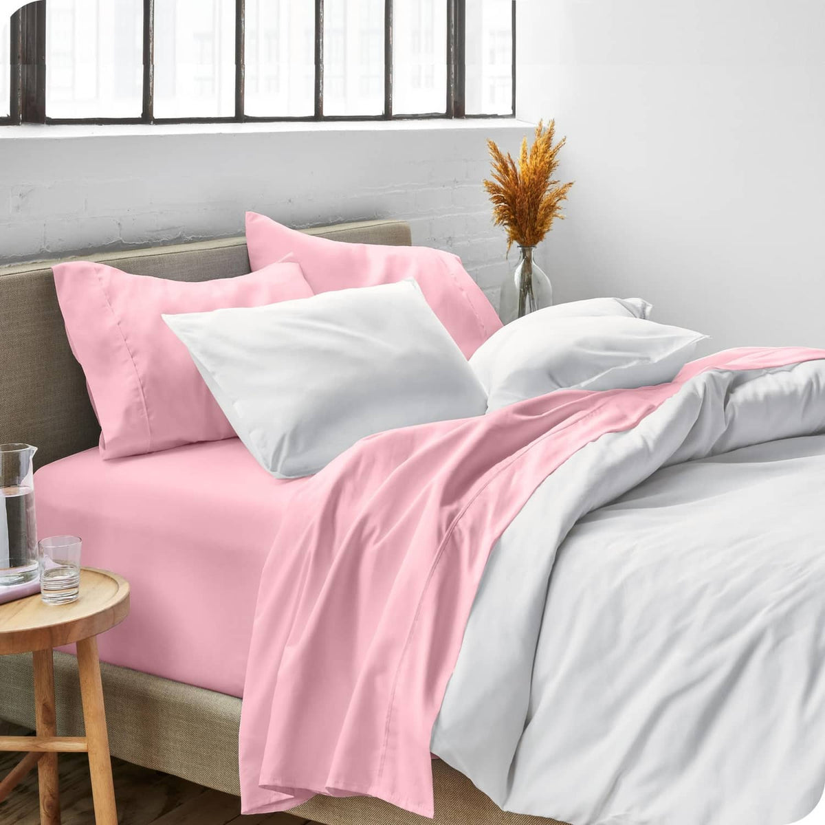 Light pink duvet cover on a bed with matching pillowcases and folded top sheet