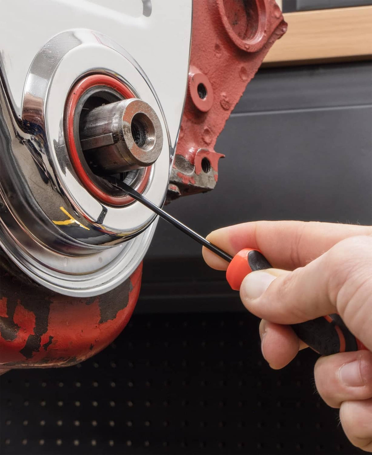 Hand using a hook pick tool on a vehicle wheel hub and brake area