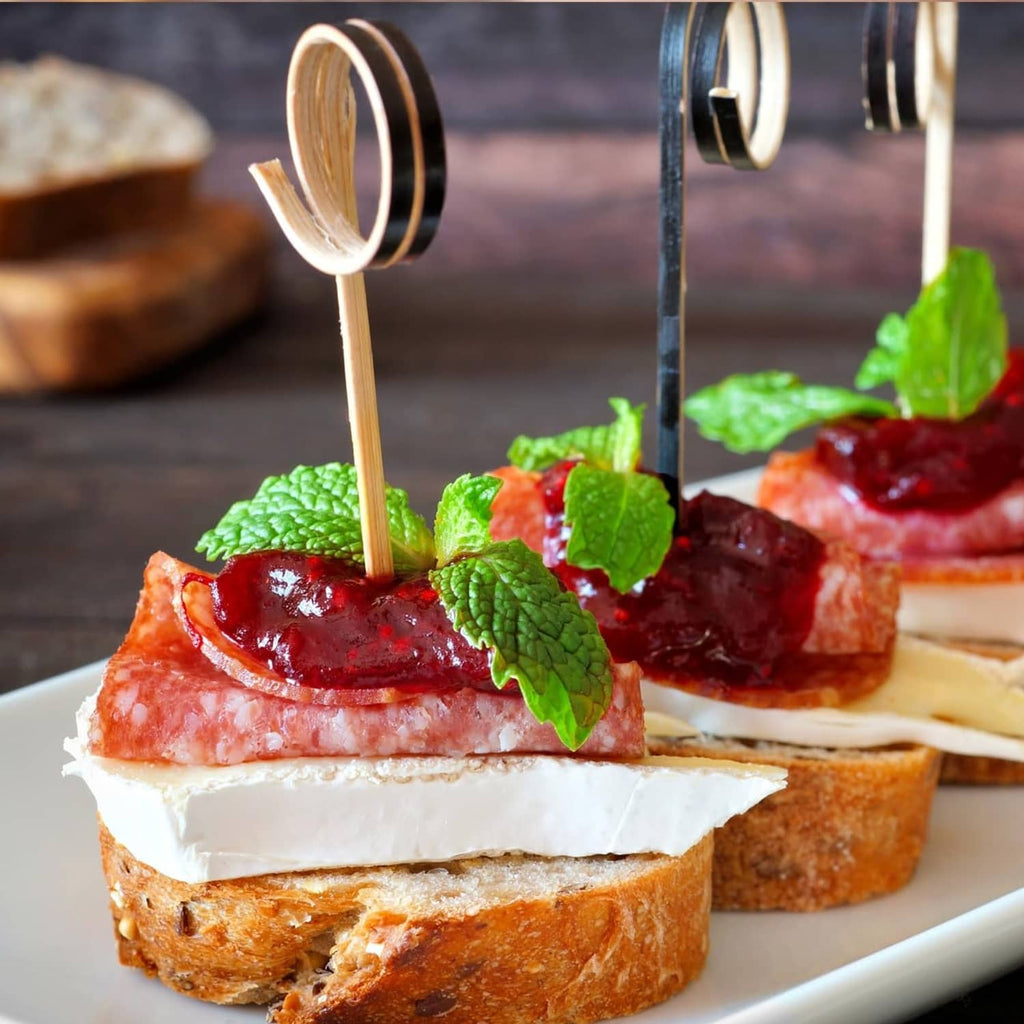 Summer sausage appetizer bites with cream cheese, jam, and mint on toast