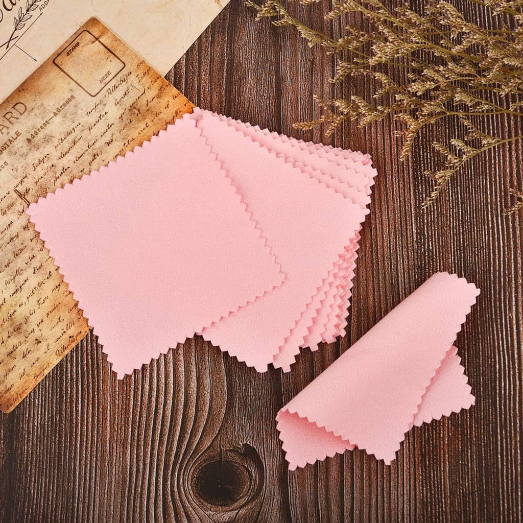 Stack of pink jewelry cleaning cloths with serrated edges on wooden surface