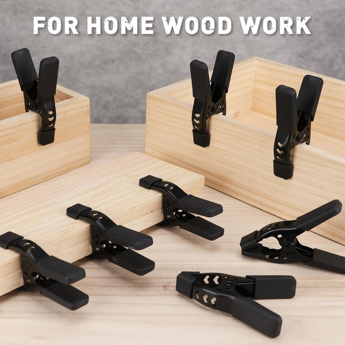 Black spring clamps holding wooden boards together, multiple clips with hinged jaws