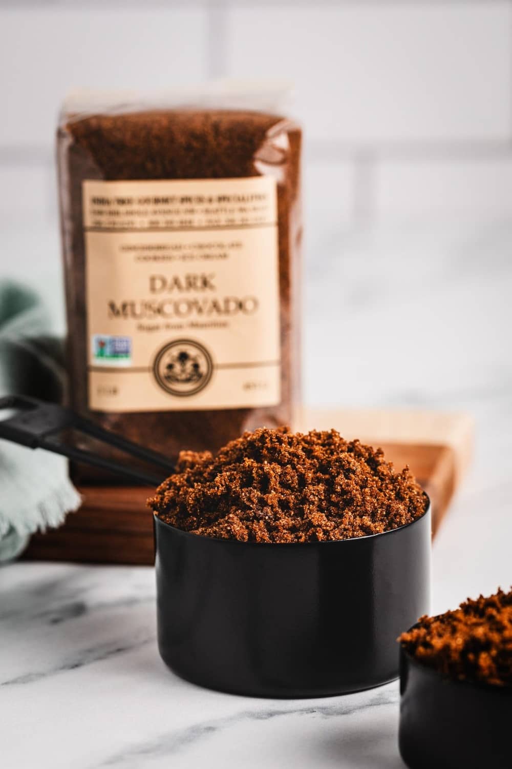 Dark muscovado sugar granules in black cups with boxed pouch