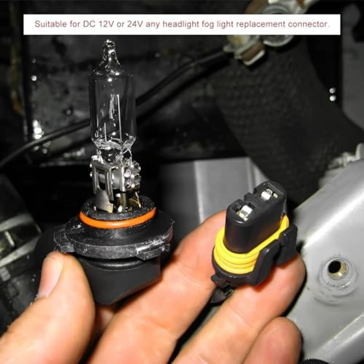 Hands holding headlight socket connectors with yellow rings and red/black wire leads