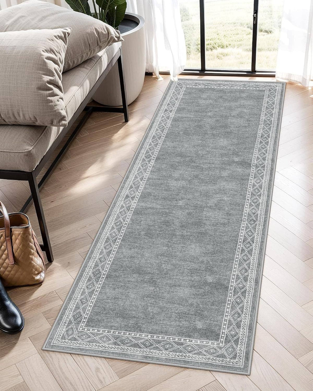 Gray runner rug lying flat, featuring a narrow geometric border and corner medallions