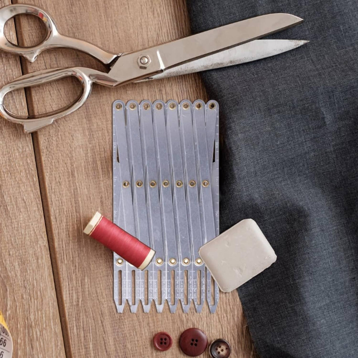 Aluminum expanding sewing gauge with evenly spaced divider plates and brass eyelets