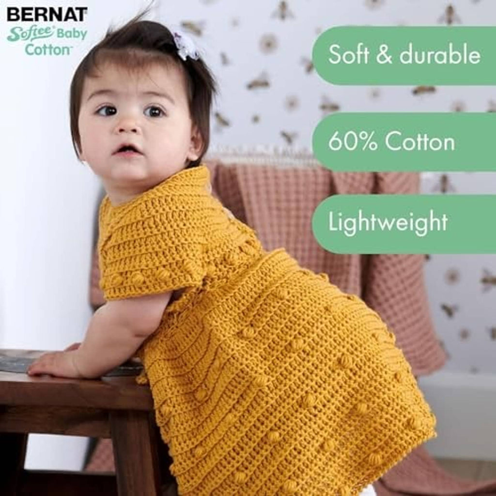 Baby wearing a mustard yellow knit blanket-style garment