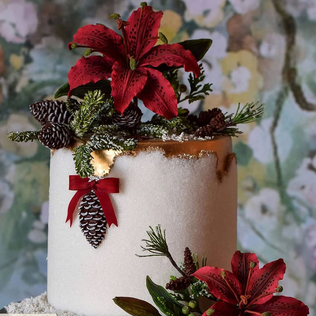 Winter cake topper with red poinsettia flowers and green pinecone foliage accents