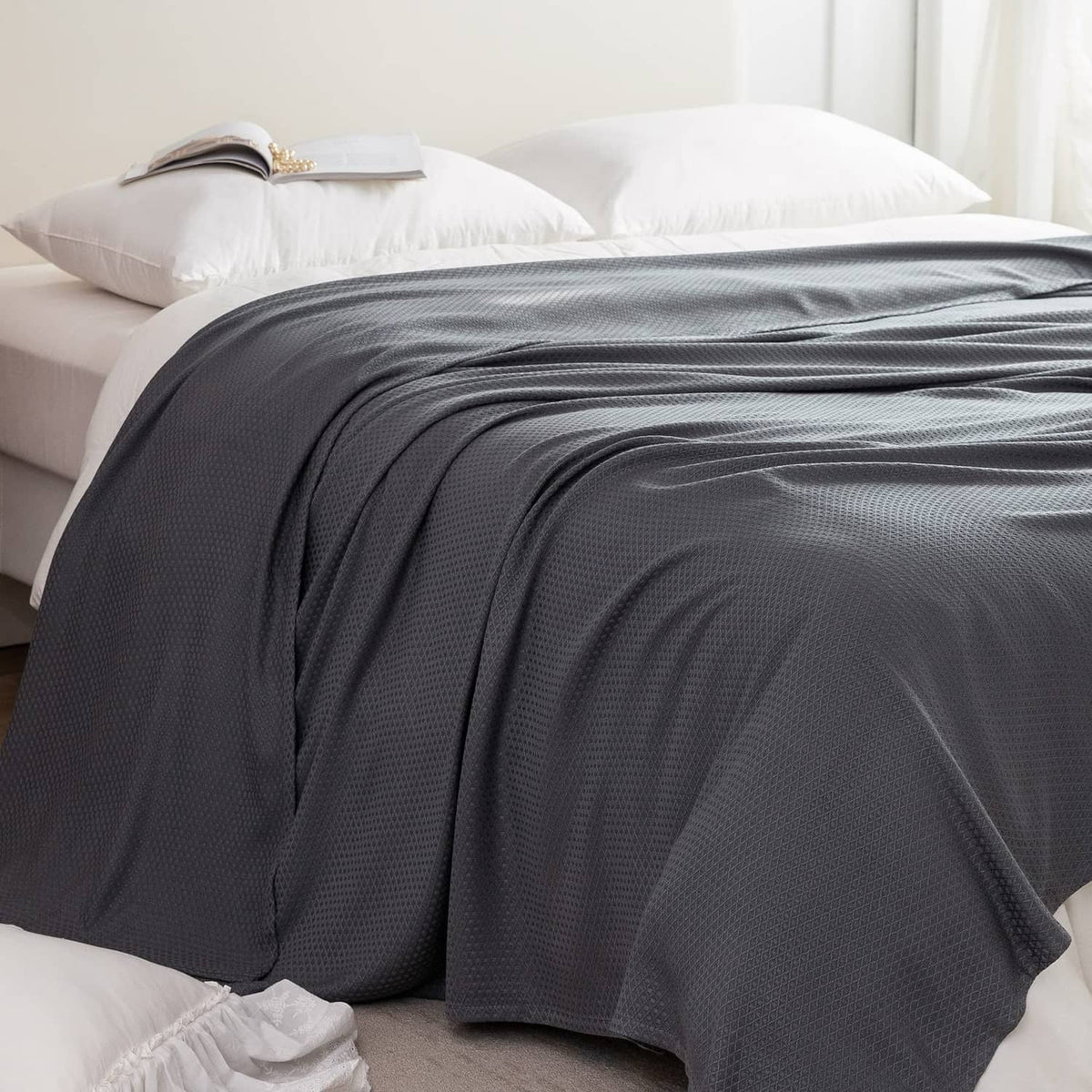 Dark gray cooling blanket spread on a bed, waffle-like textured weave