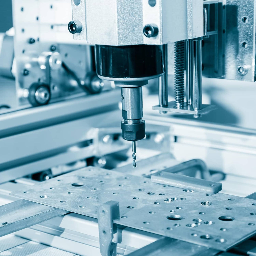 Silver aluminum flat bar clamped on a machine bed with a drill bit above.