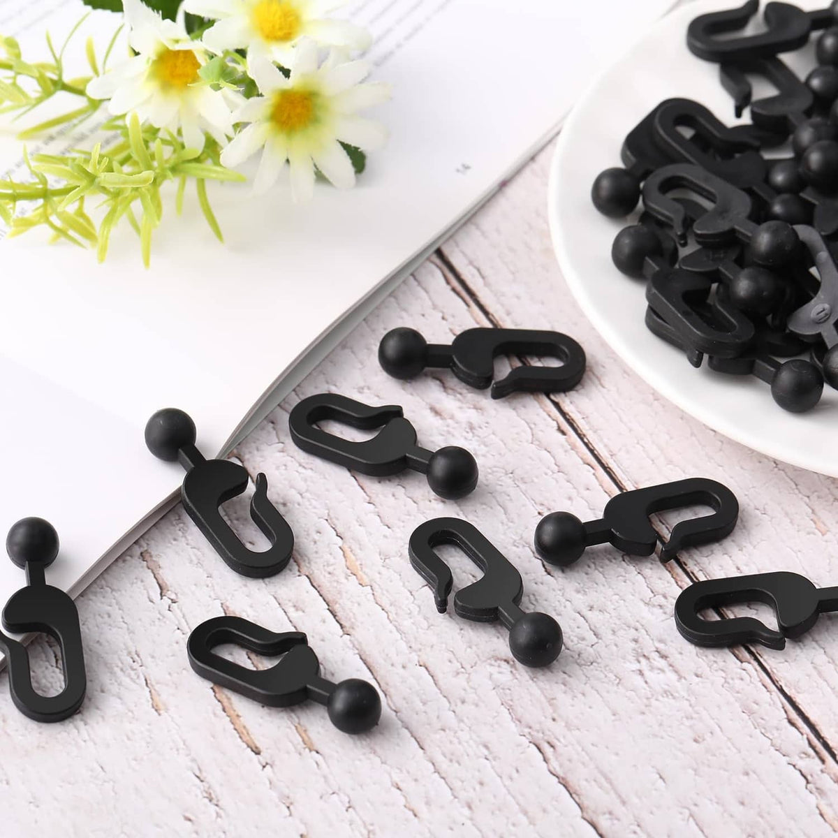 Close-up of black plastic curtain hook clips with ball tips, C-shaped design