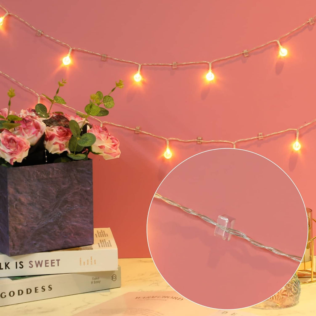 Clear adhesive light clip securing warm fairy lights to a thin string wire.