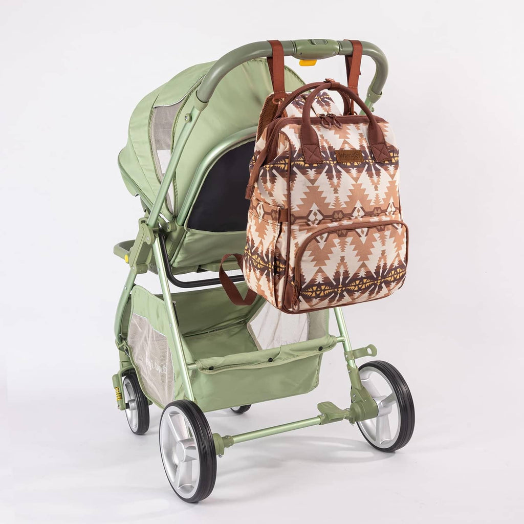 Wrangler Callie diaper bag, beige aztec print with brown trim on a green stroller