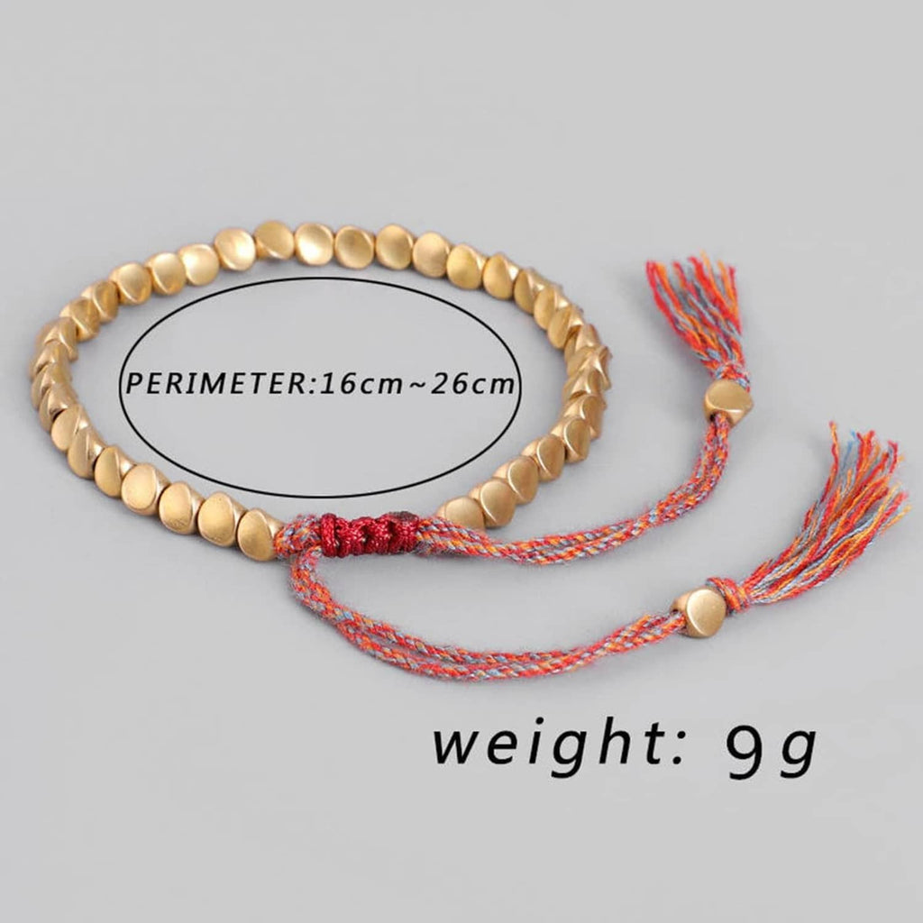 Flat lay of gold-tone bead bracelet with red knot and cord tassels, measured.