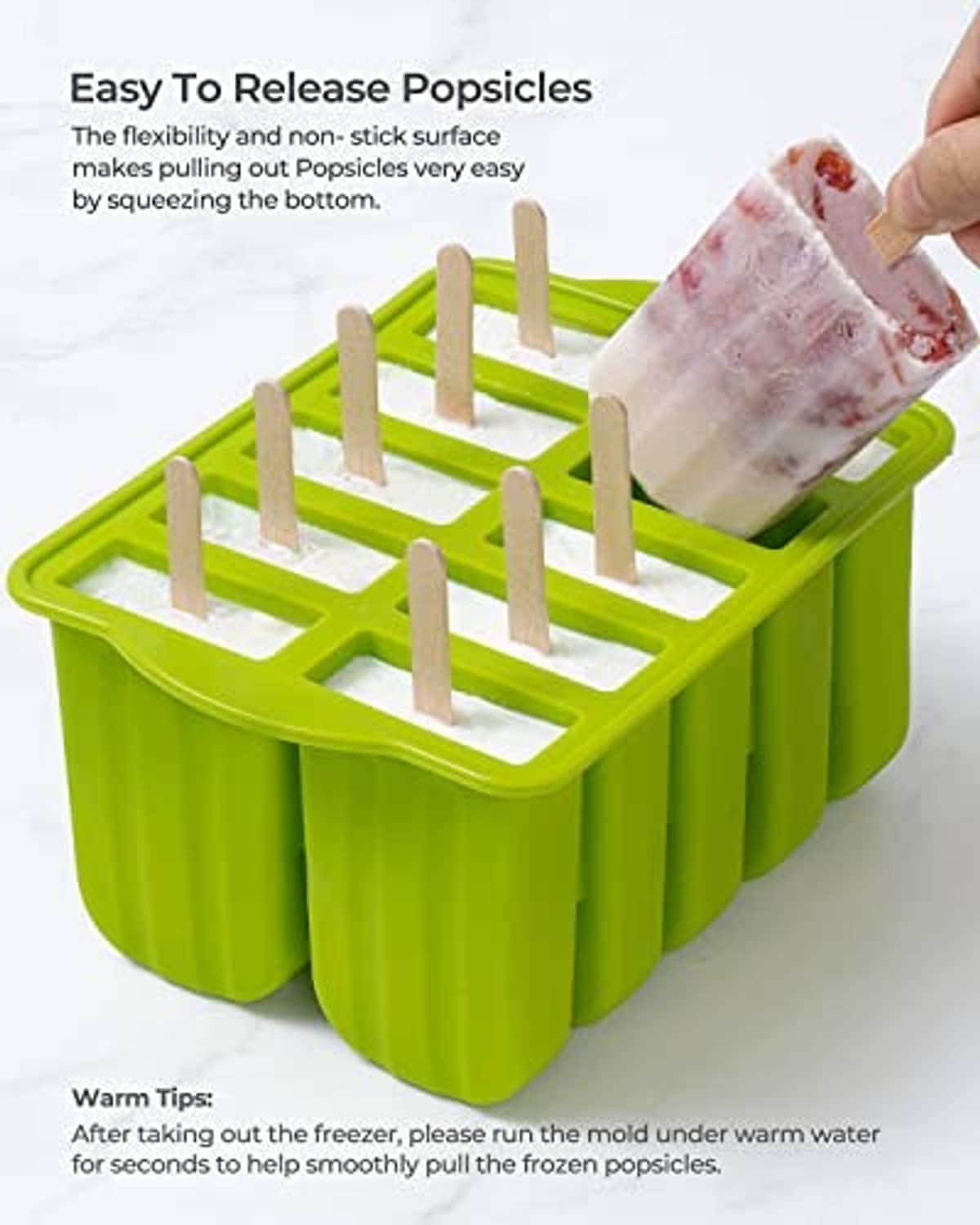 Green popsicle mold with holders as one popsicle is lifted out by hand