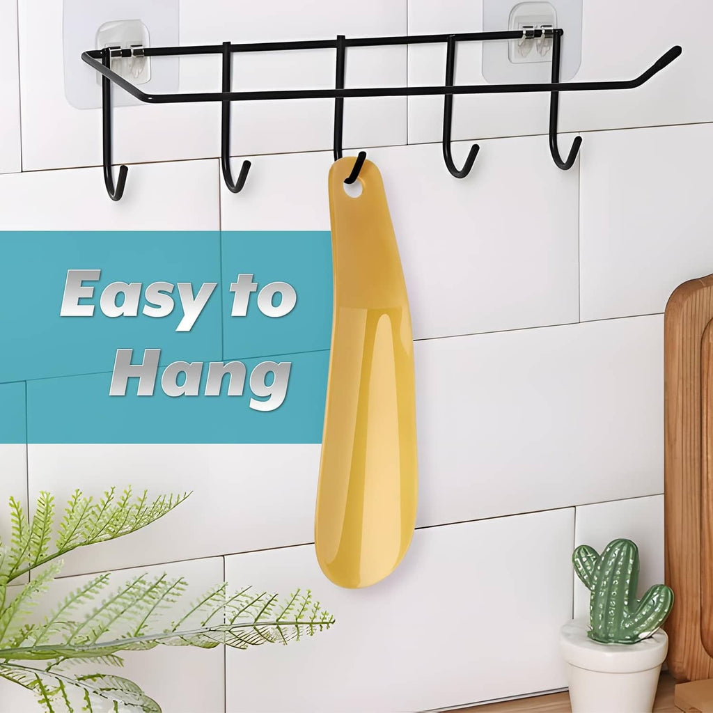 Yellow plastic shoe horn hanging on a black wall hook rack