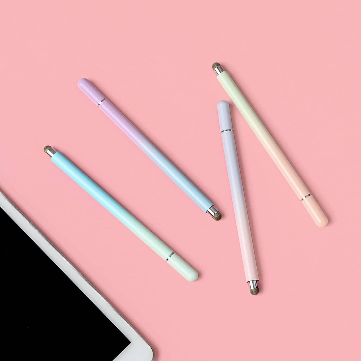 Four colored touch screen stylus pens with metal disc tips on a flat surface