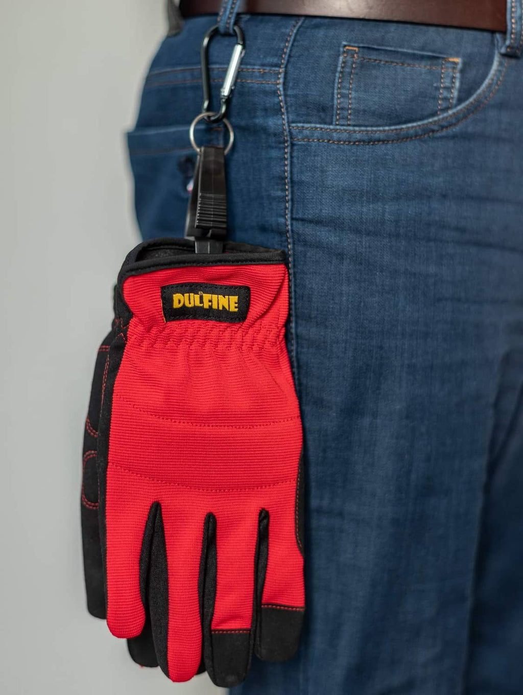 Red and black work gloves with carabiner clip, hanging from a belt loop