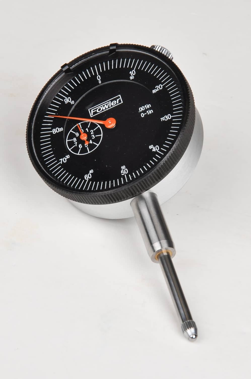 Dial indicator with black face, orange pointer, and silver probe rod