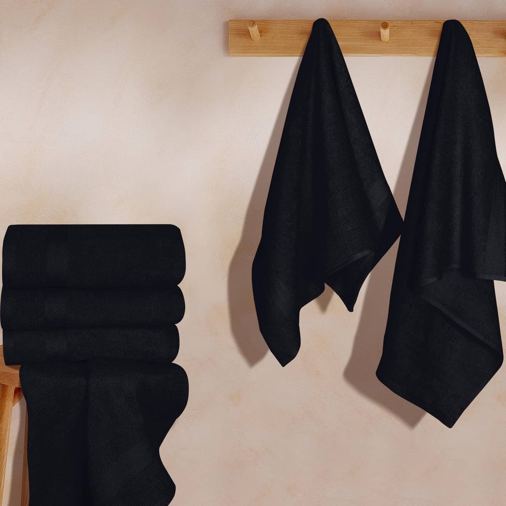 Black hand towels, folded stack with two towels hanging straight on wall hooks
