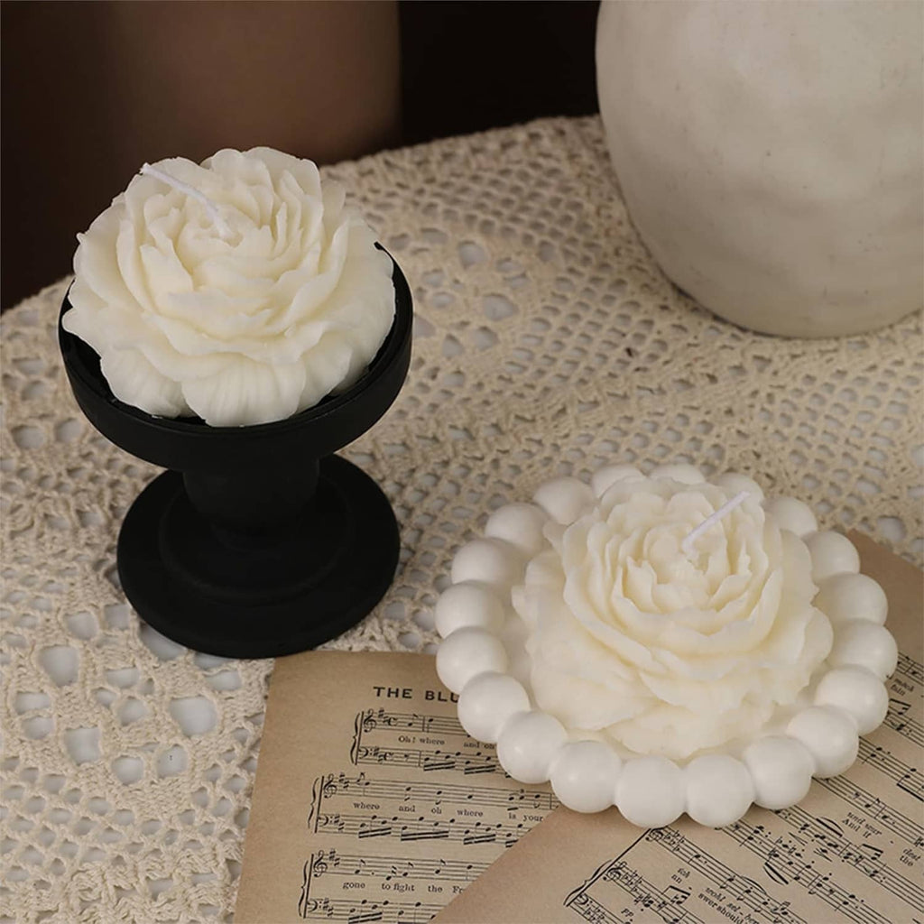White peony flower candles with detailed petals on a black pedestal and round base