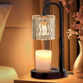 Electric candle warmer lamp with clear wavy glass shade and lit candle on black base