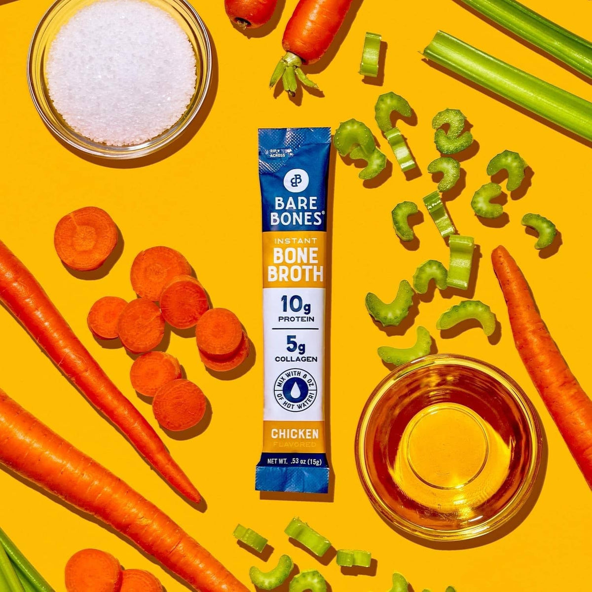 Instant bone broth powder packet with carrots, celery sticks, and jar of broth