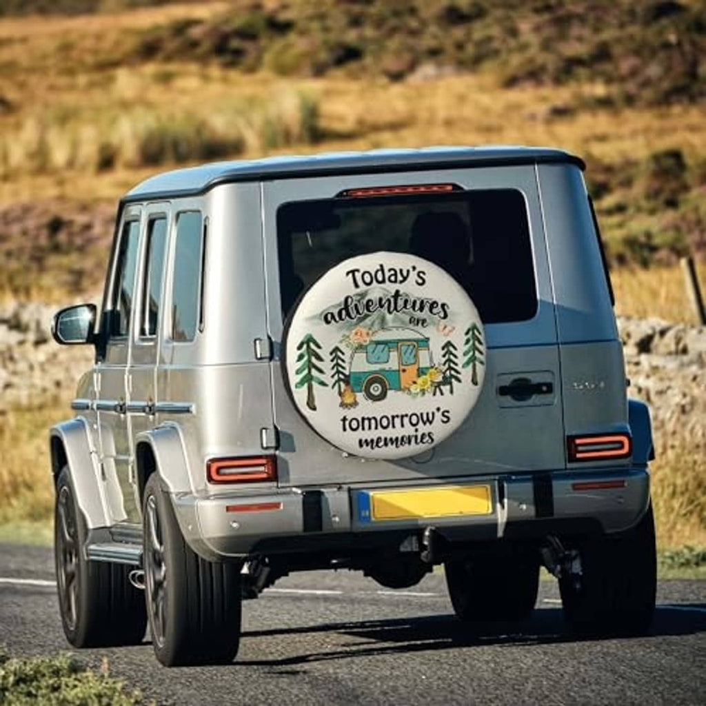 Spare tire cover on RV rear, cream with black rim, camper graphic and 'Today’s adventures...'