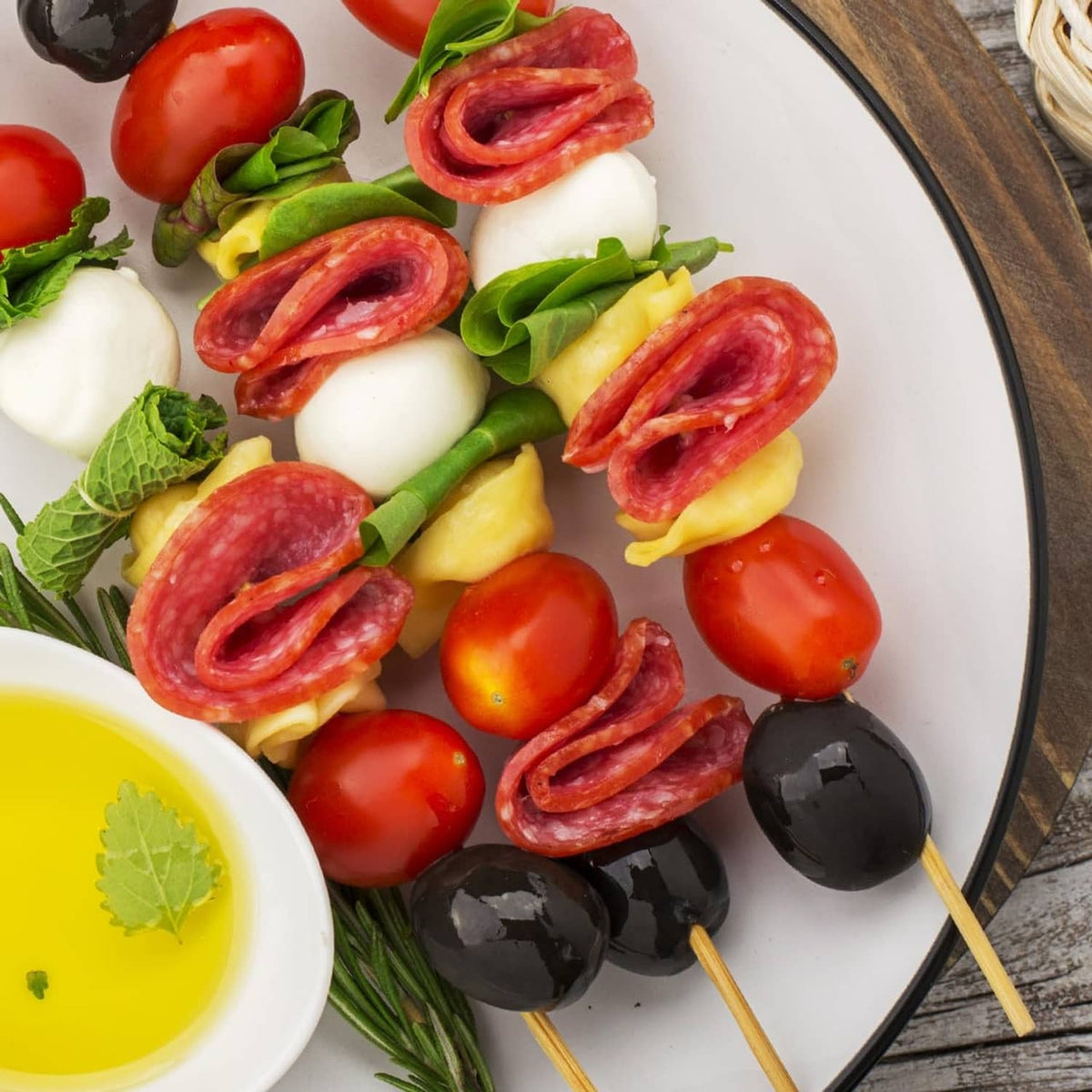 Summer sausage skewers with cheese, tomatoes, olives, and herb oil dip