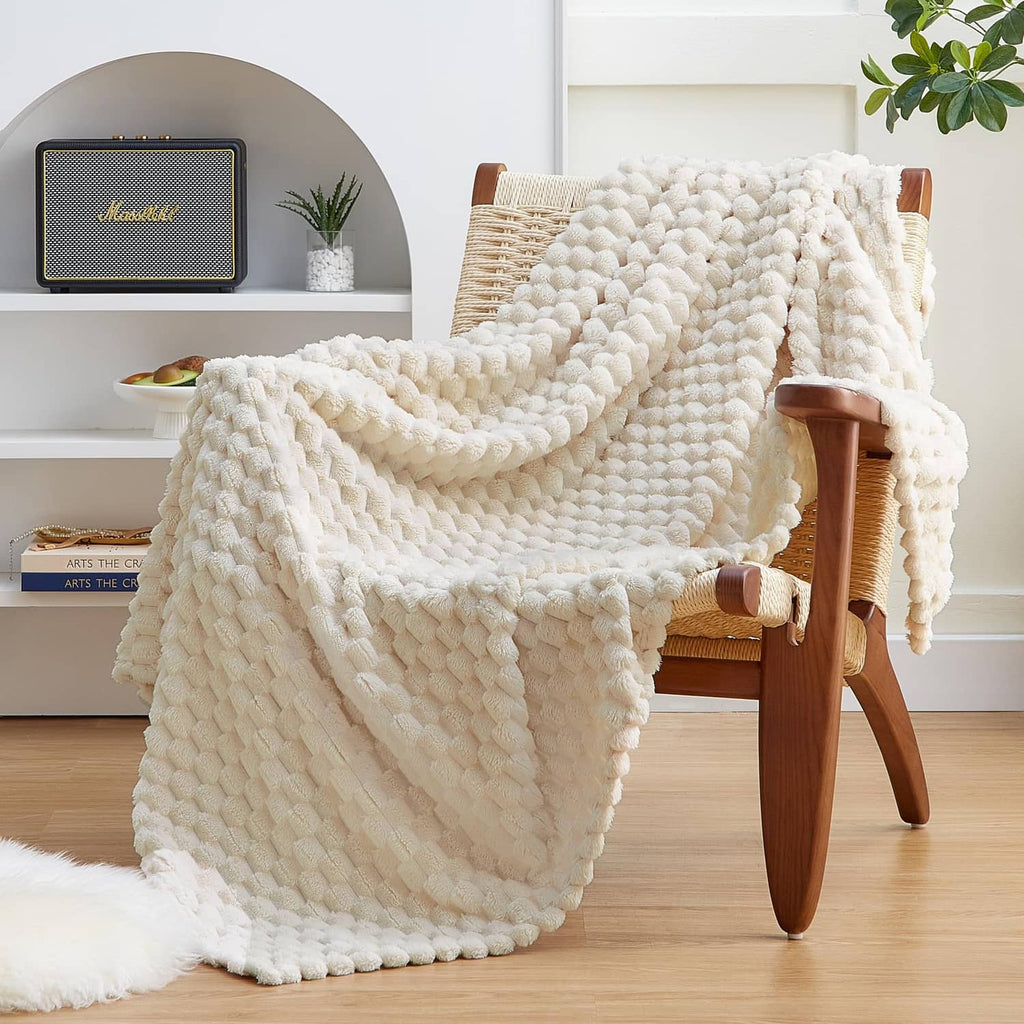 Cream fleece throw blanket with 3D pom-pom texture, draped over chair