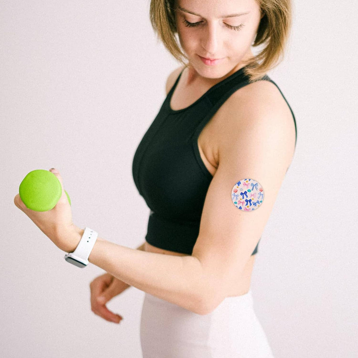 Round multicolor bow-print sensor patch on a woman’s upper arm