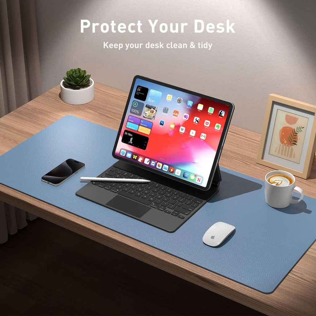 Denim blue desk pad protector on a wooden desk beneath laptop and mouse