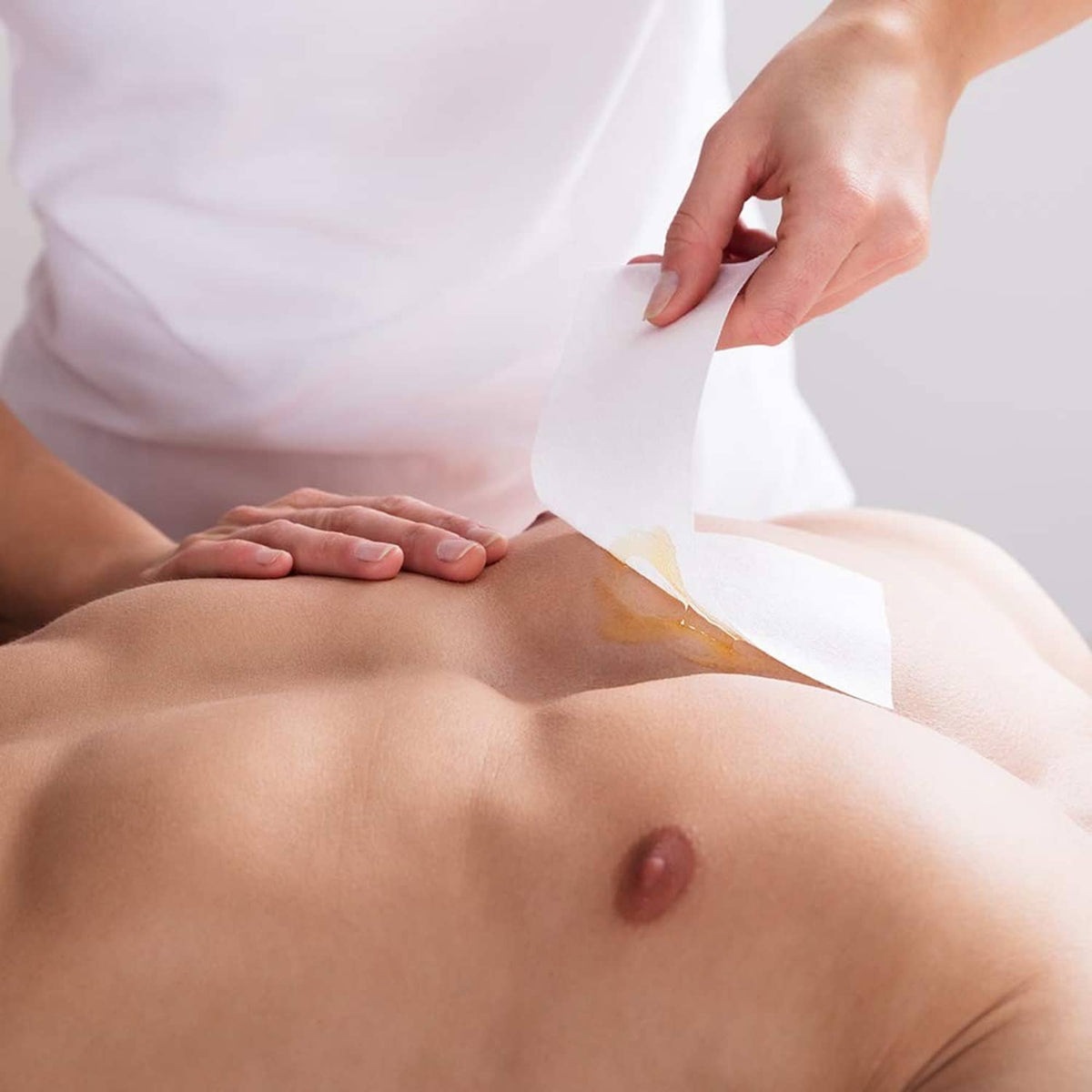White non-woven epilating strip being applied to skin