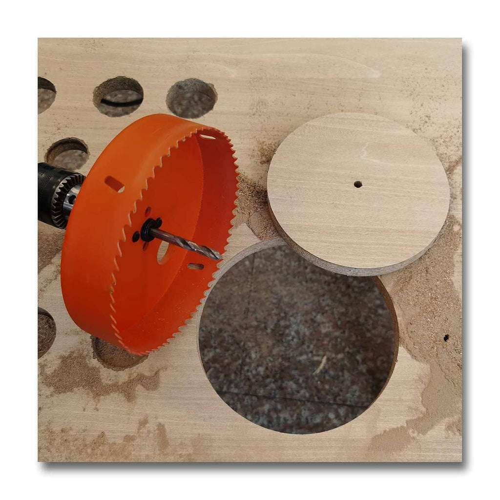 Orange hole saw with arbor and circular pilot drill bit, on wood surfaces