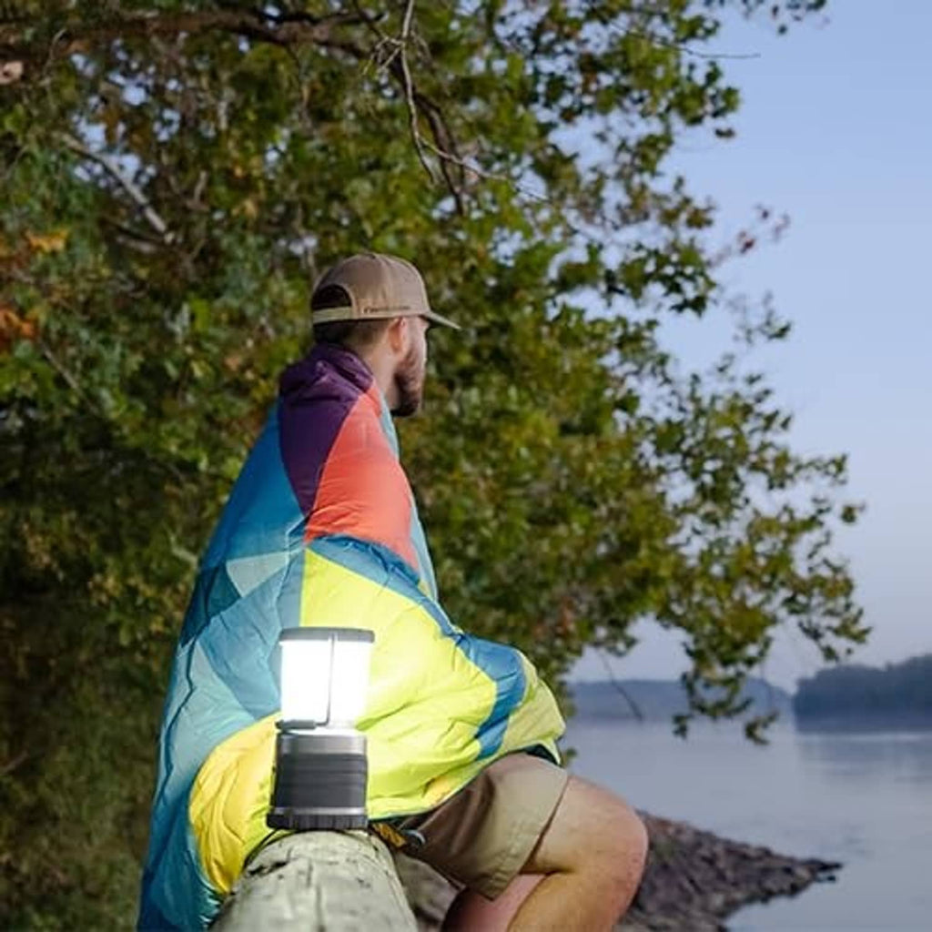 Outdoor lantern held by person in colorful jacket, glowing near the hand