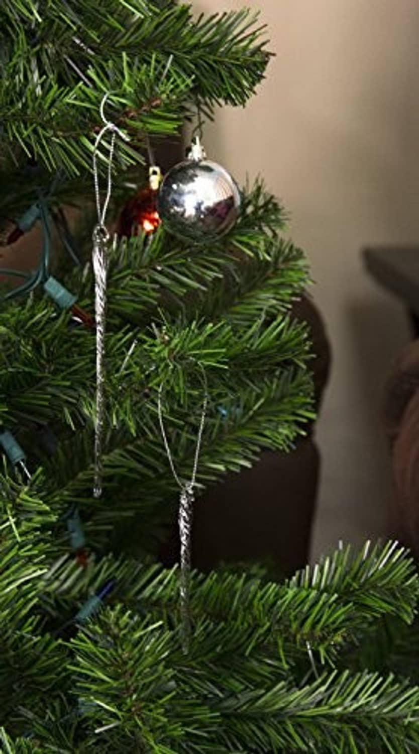 Clear glass icicle ornament hanging on a tree branch with silver-tone loop
