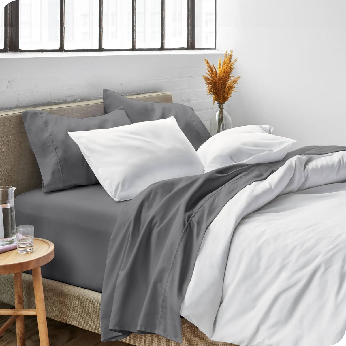 Grey sheet set with white pillowcases on bed, pillows arranged on top