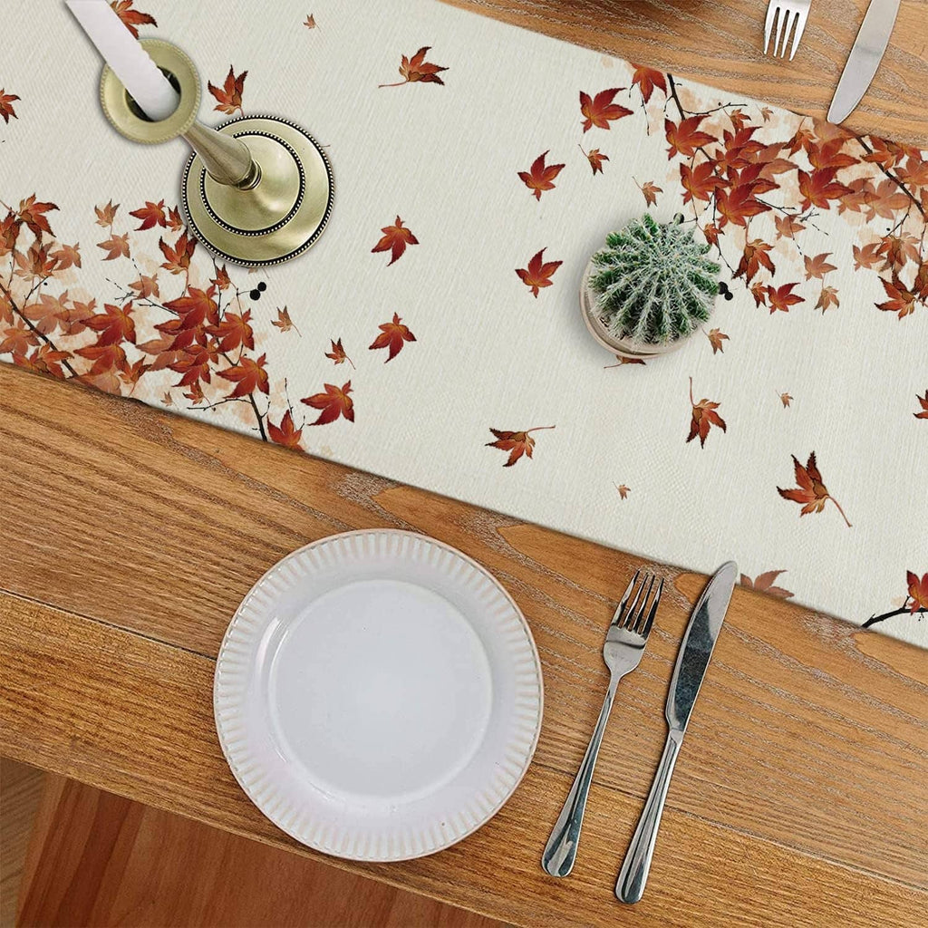 White table runner with cat, pumpkins, and red autumn leaves on a dining table
