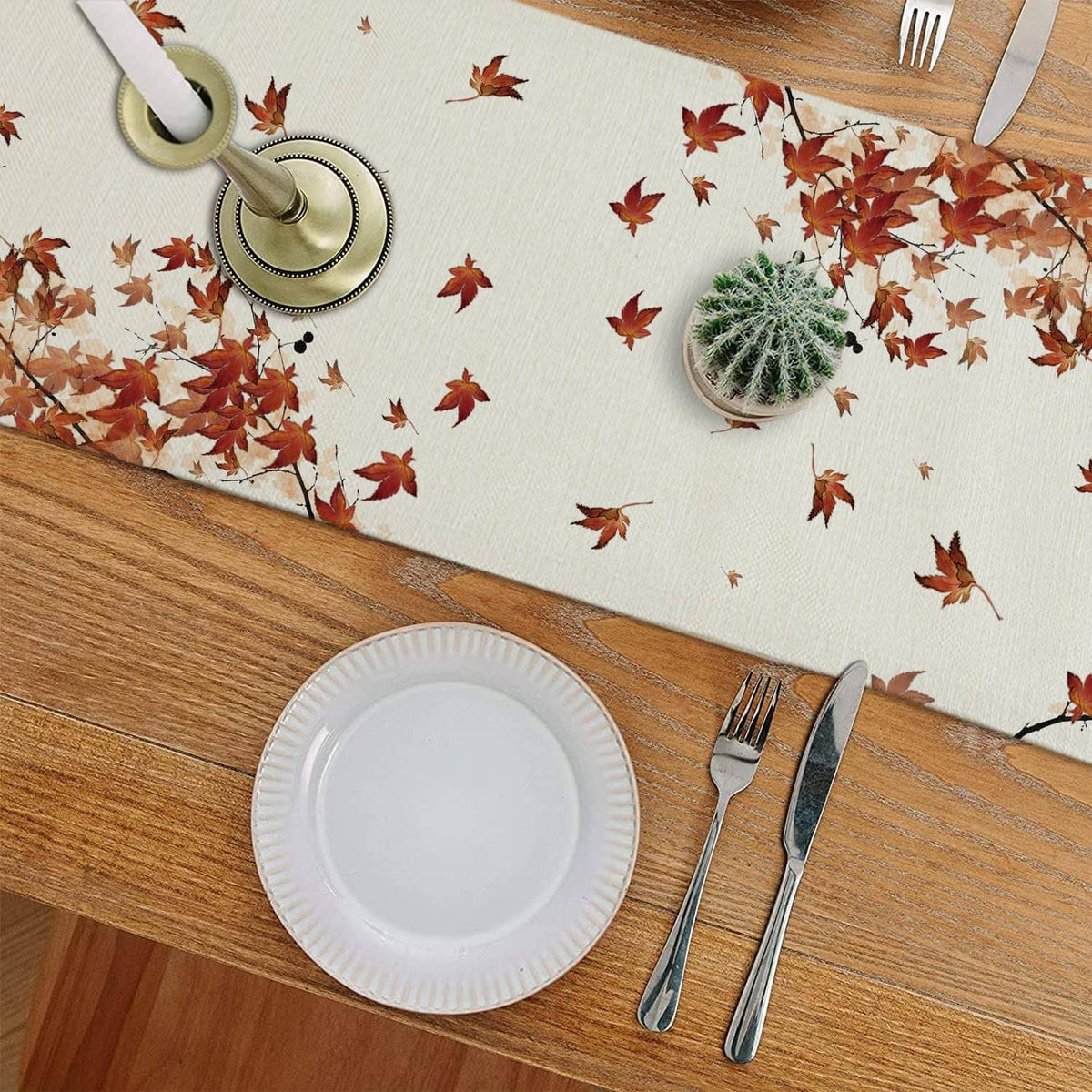 White table runner with cat, pumpkins, and red autumn leaves on a dining table
