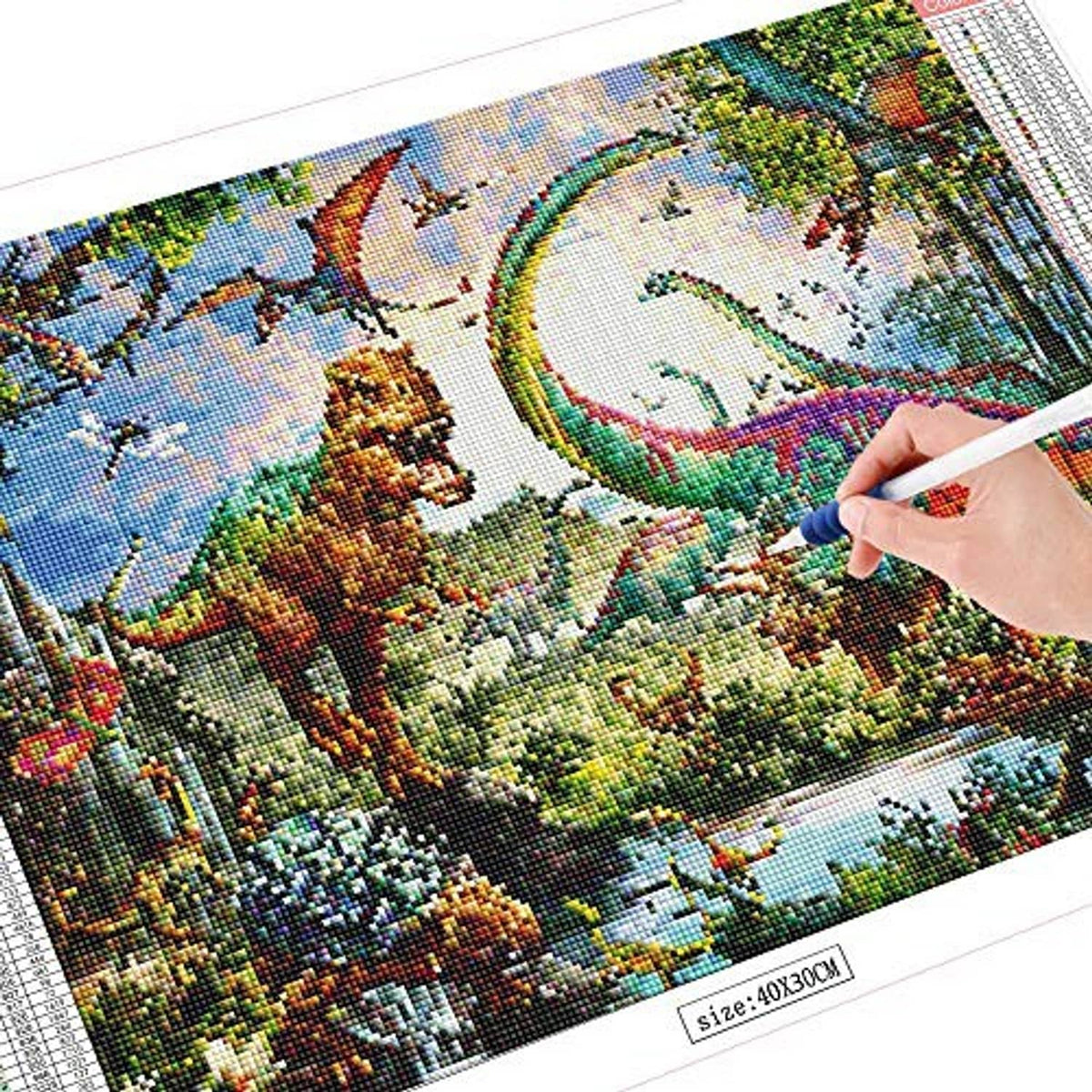 Diamond art canvas detail with resin diamonds being placed along a dinosaur landscape.