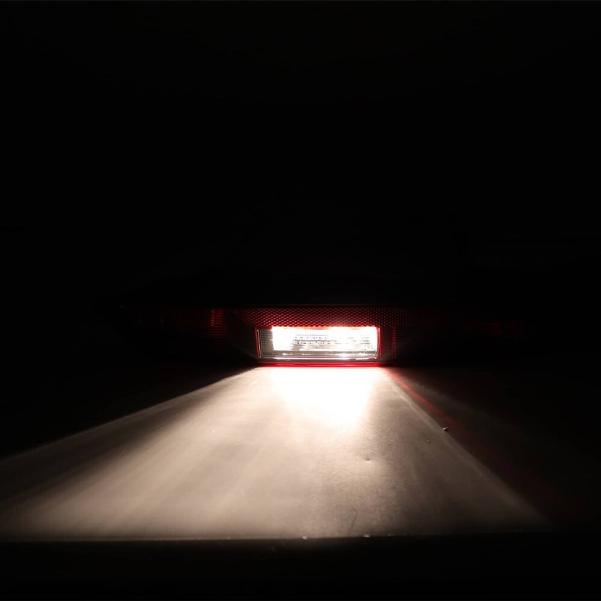 Rear tail light glowing white with red accents in dark housing